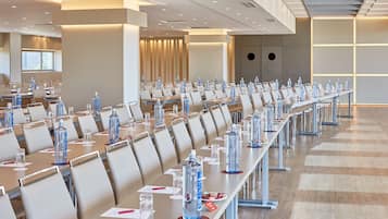 A conference room with rows of tables, chairs, and water bottles.