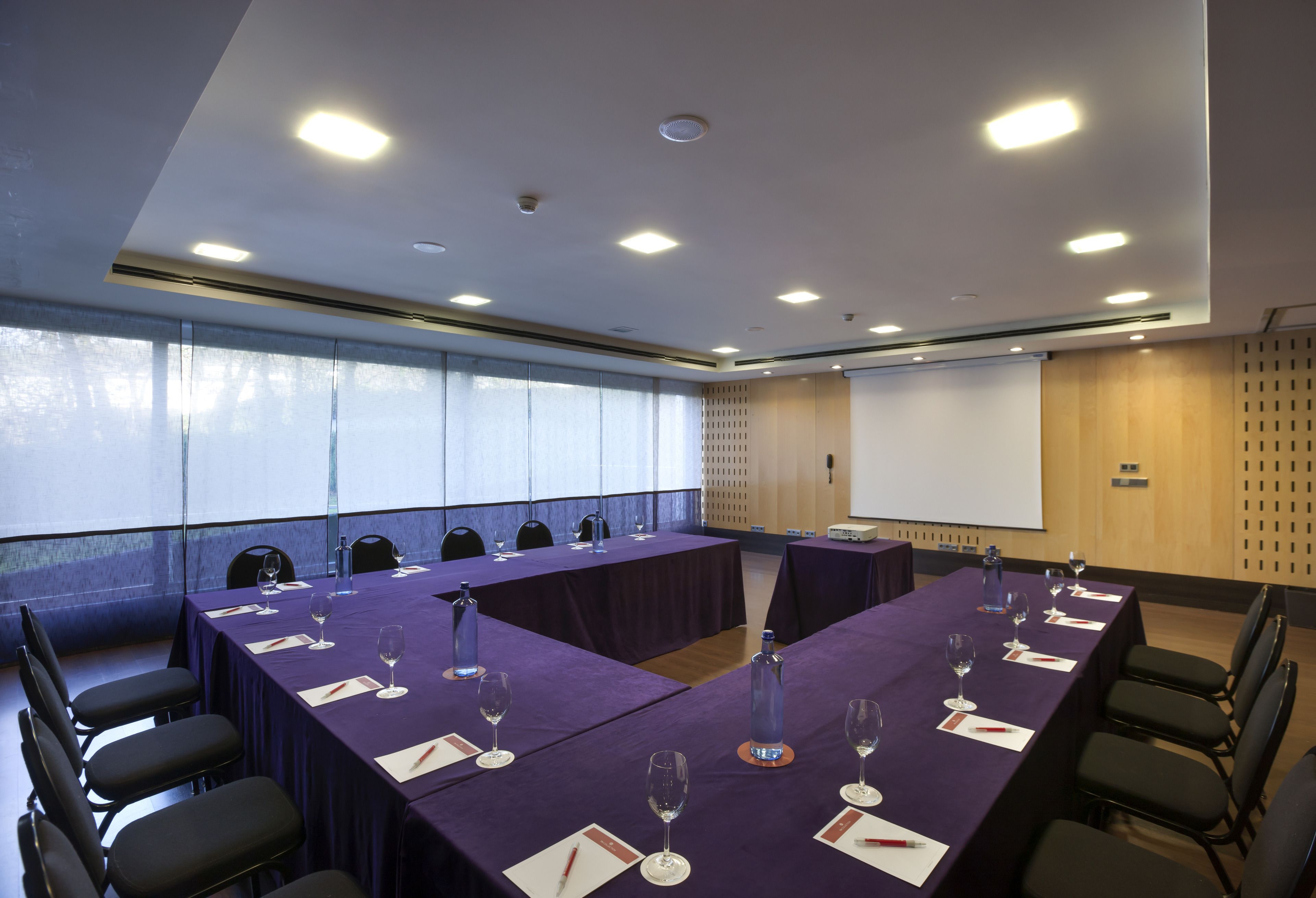 A conference room with a long table, chairs, and a projector screen.