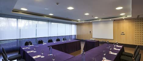 A conference room with a long table, chairs, and a projector screen.