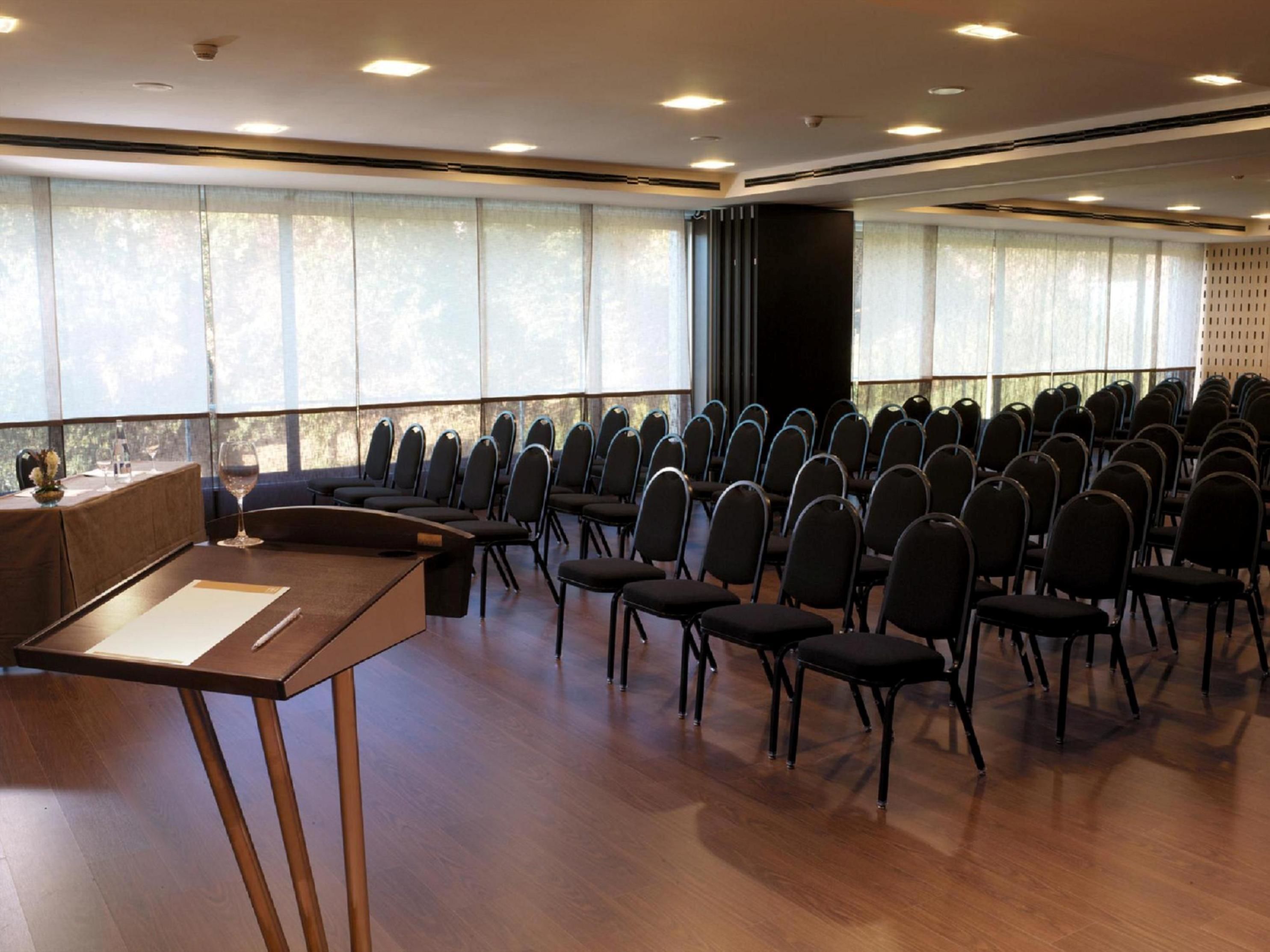 A conference room with rows of chairs, a podium, and large windows.
