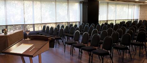 A conference room with rows of chairs, a podium, and large windows.