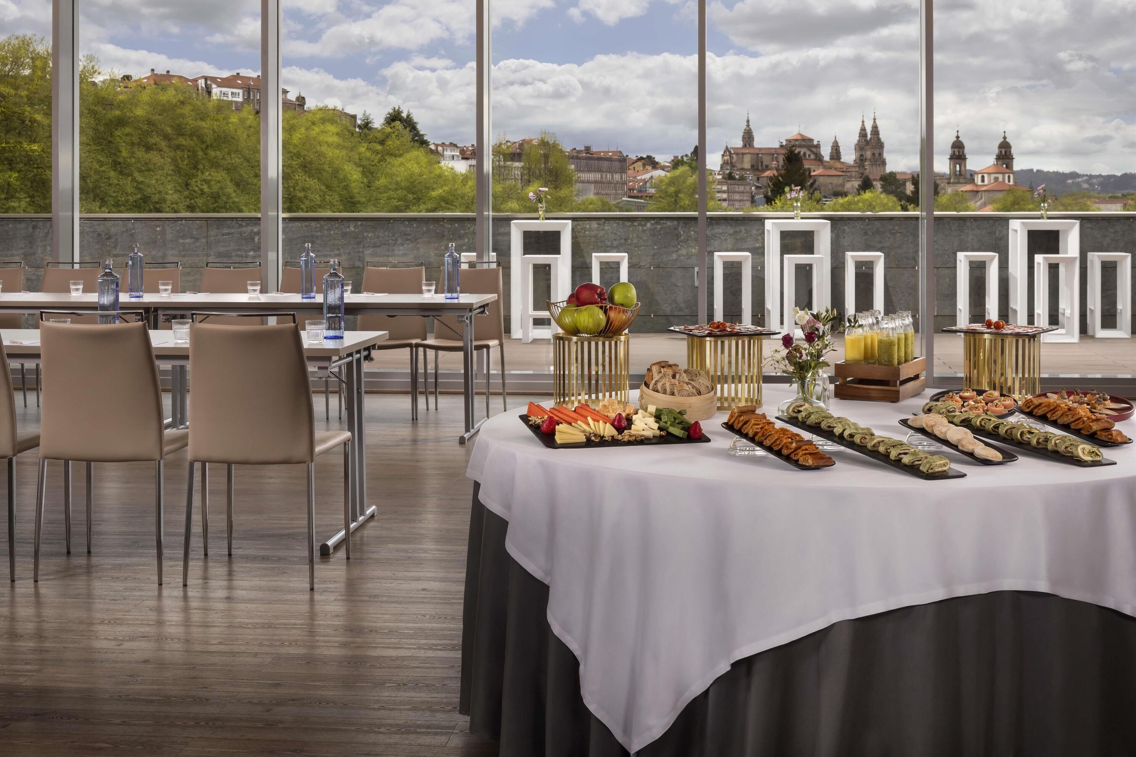 A rooftop dining area with a buffet table, chairs, and a scenic view of a historic cityscape.