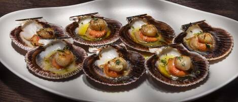 A white plate with eight scallops arranged in a semi-circle.