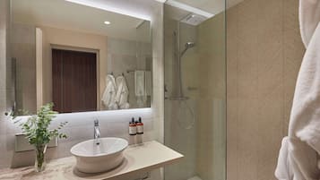 A modern bathroom with a large mirror, a white sink, and a glass-enclosed shower.