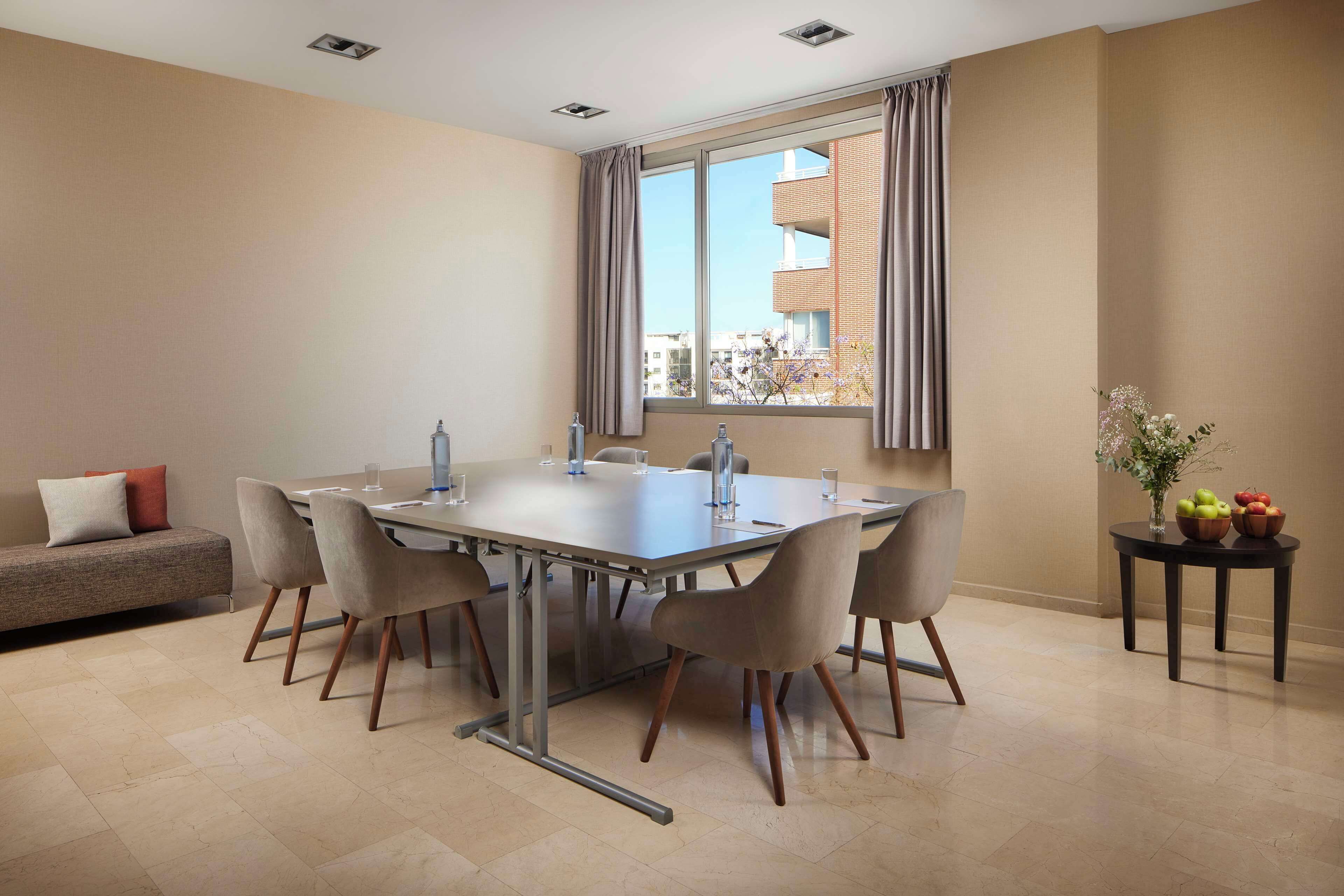 Uma área de refeições moderna com uma mesa grande, cadeiras, um sofá e uma janela com cortinas.