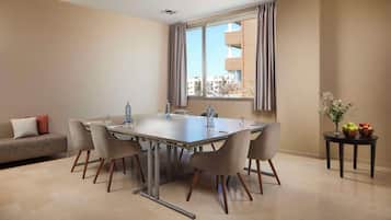 Uma área de refeições moderna com uma mesa grande, cadeiras, um sofá e uma janela com cortinas.