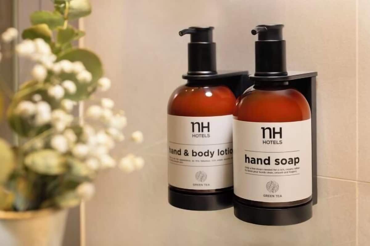 Zwei Flaschen Handseife und Lotion mit Pumpspender, beschriftet mit 'NH Hotels' und 'GRÜNER TEE'.