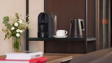 Een moderne kamer met een koffiezetapparaat, een kop en een bloemenvaas op een glazen tafel.