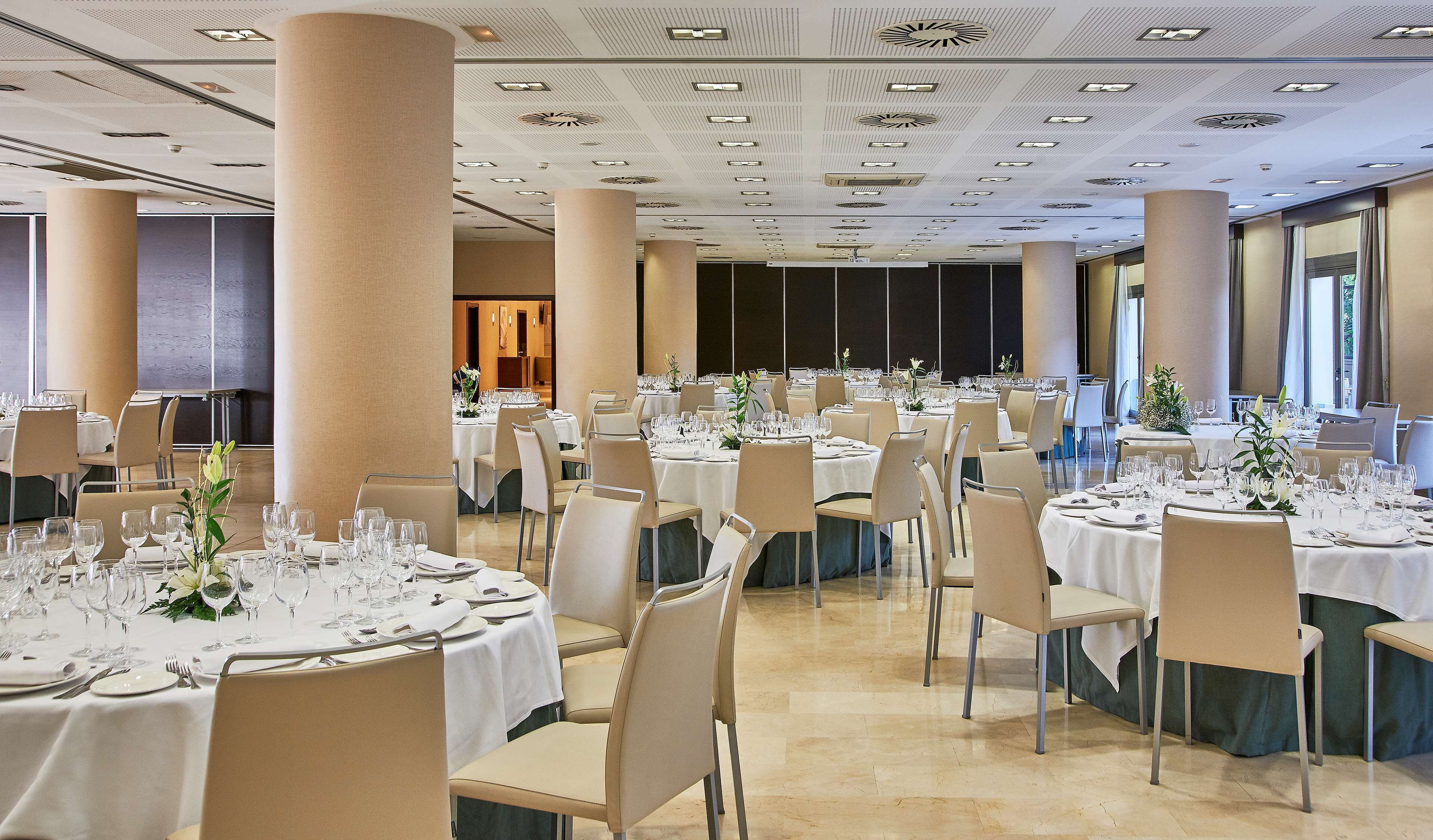 A banquet hall with round tables set for dining, featuring white tablecloths and chairs.