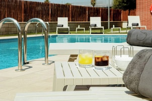 A poolside area with lounge chairs, a table with drinks, and a towel.