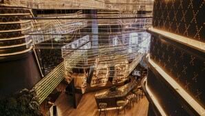Un bar con varios niveles y un diseño moderno, que cuenta con una escalera central y diferentes zonas de estar.