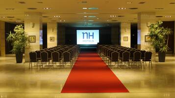 Un vestíbulo de hotel con una alfombra roja que conduce a una zona de estar con filas de sillas.
