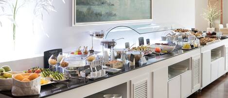 Una mesa de buffet con diferentes alimentos y salsas, un cuadro en la pared y un jarrón con flores blancas.