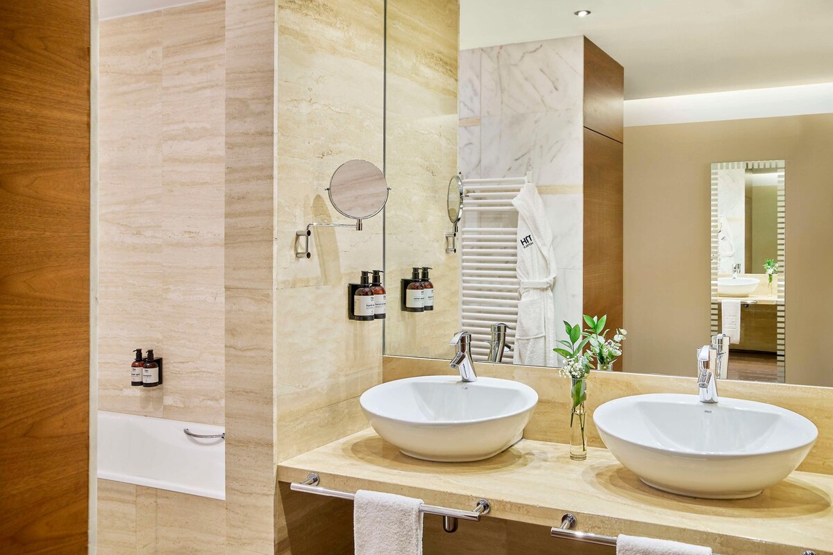 A modern bathroom with two large sinks, a mirror, and a towel rack.