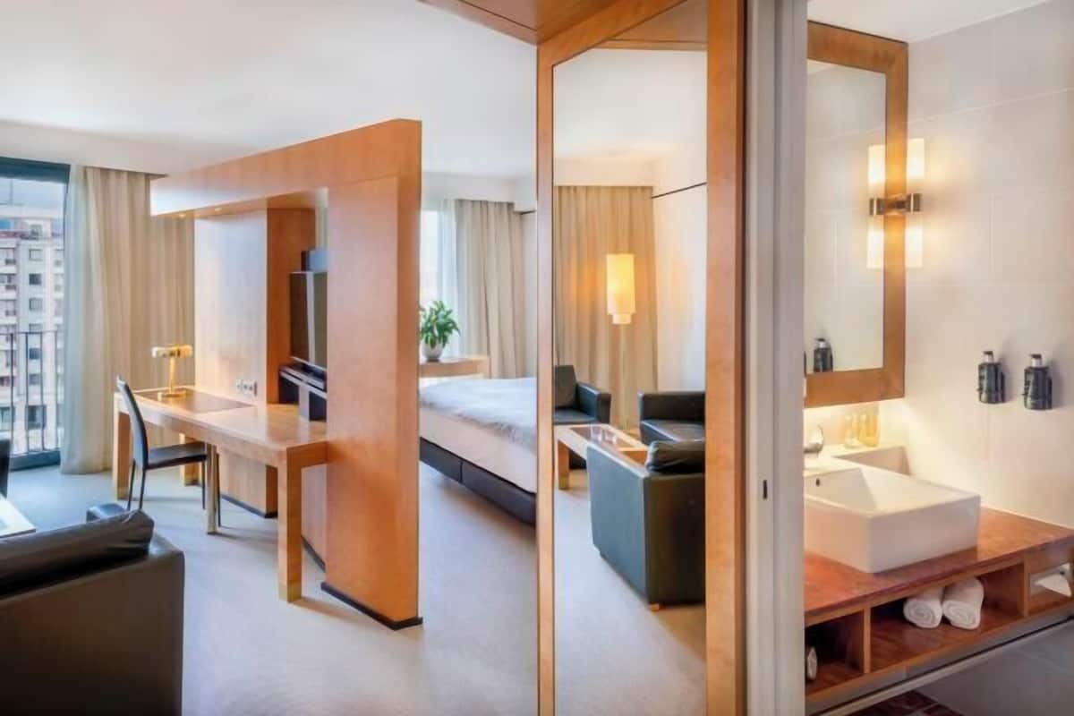 A modern hotel room with a bed, desk, and bathroom.