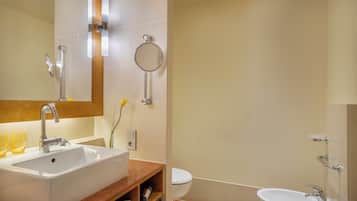 Un baño con un espejo grande, dos lavamanos, un inodoro y una zona de ducha.