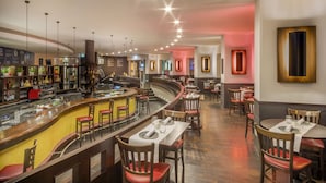 A restaurant with a curved bar, wooden chairs, and tables set for dining. - Melia Berlin (Berlin)