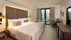 A hotel room with a large bed, a desk, a chair, and a television. - Melia Berlin (Berlin)