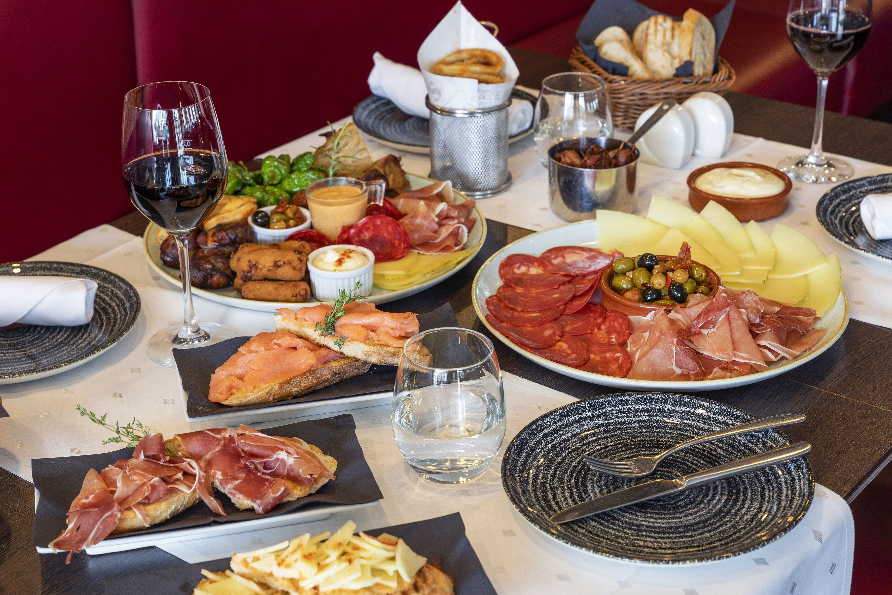 Una mesa dispuesta con diversos alimentos, incluyendo pan, queso y embutidos, junto con copas de vino.
