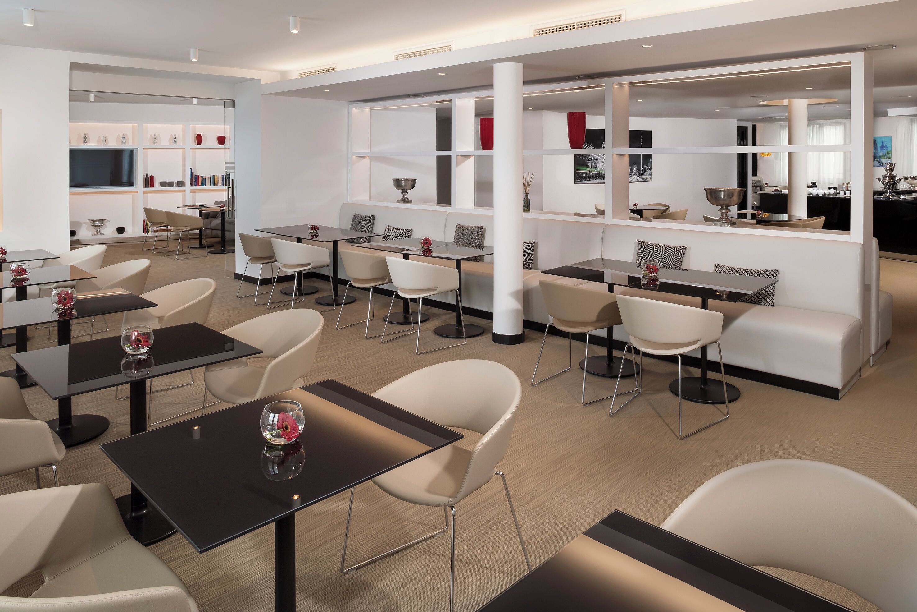 Um restaurante moderno com várias áreas de refeição, incluindo um bar e uma área de estar com sofás e mesas.