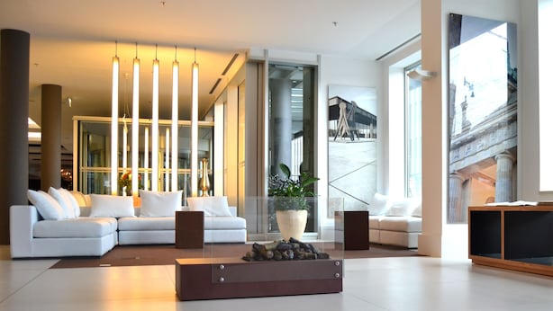A modern living room with a sectional sofa, a coffee table, and a large window with a cityscape view. - Melia Berlin (Berlin)