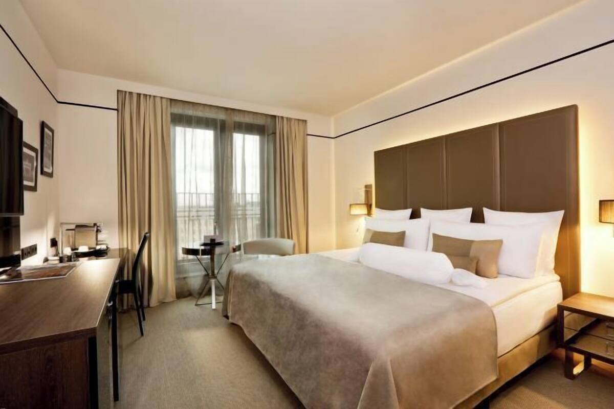 A hotel room with a large bed, a desk, and a chair.