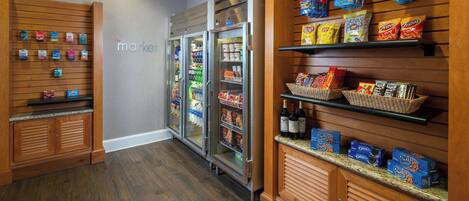 A grocery store interior with wooden shelves, refrigerated cases, and a variety of snacks and beverages.