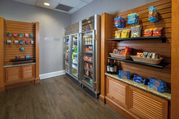 A grocery store interior with wooden shelves, refrigerated cases, and a variety of snacks and beverages.