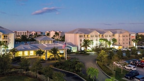 A hotel with a large parking lot, multiple buildings, and a well-lit entrance.