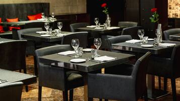 A restaurant with round tables, black chairs, and a brick wall in the background.