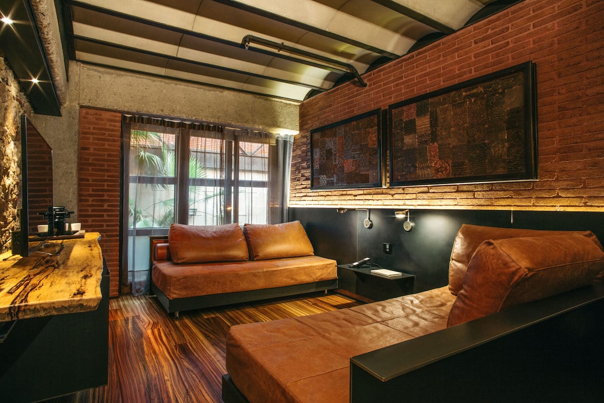 Un intérieur moderne avec un mur en briques, un canapé, un plancher en bois et une machine à café.