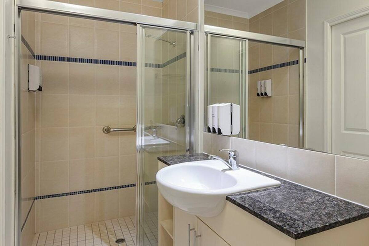 Un baño con ducha de vidrio, un lavabo blanco y un espejo.