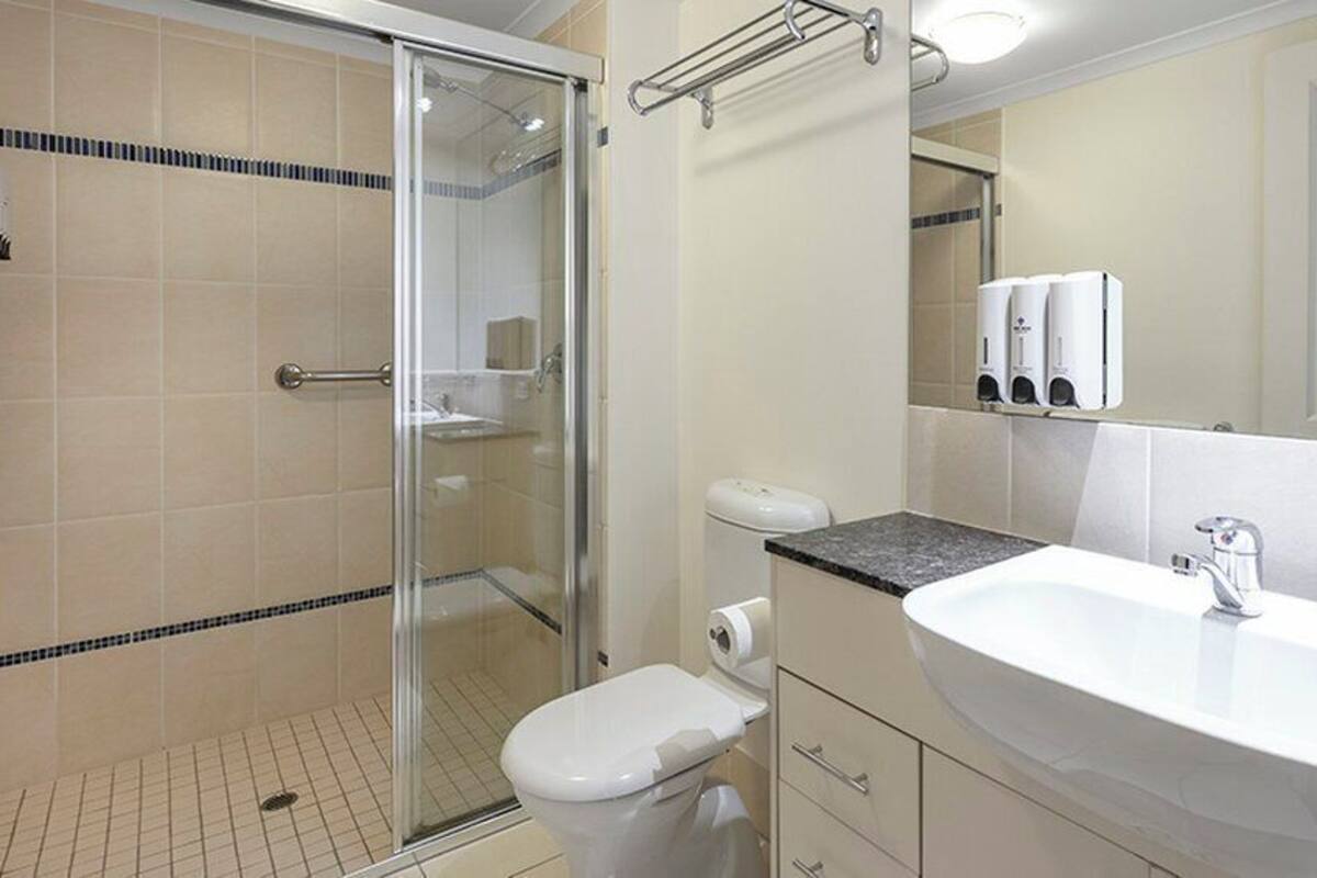 Un baño con cabina de ducha de vidrio, inodoro, lavabo y espejo.