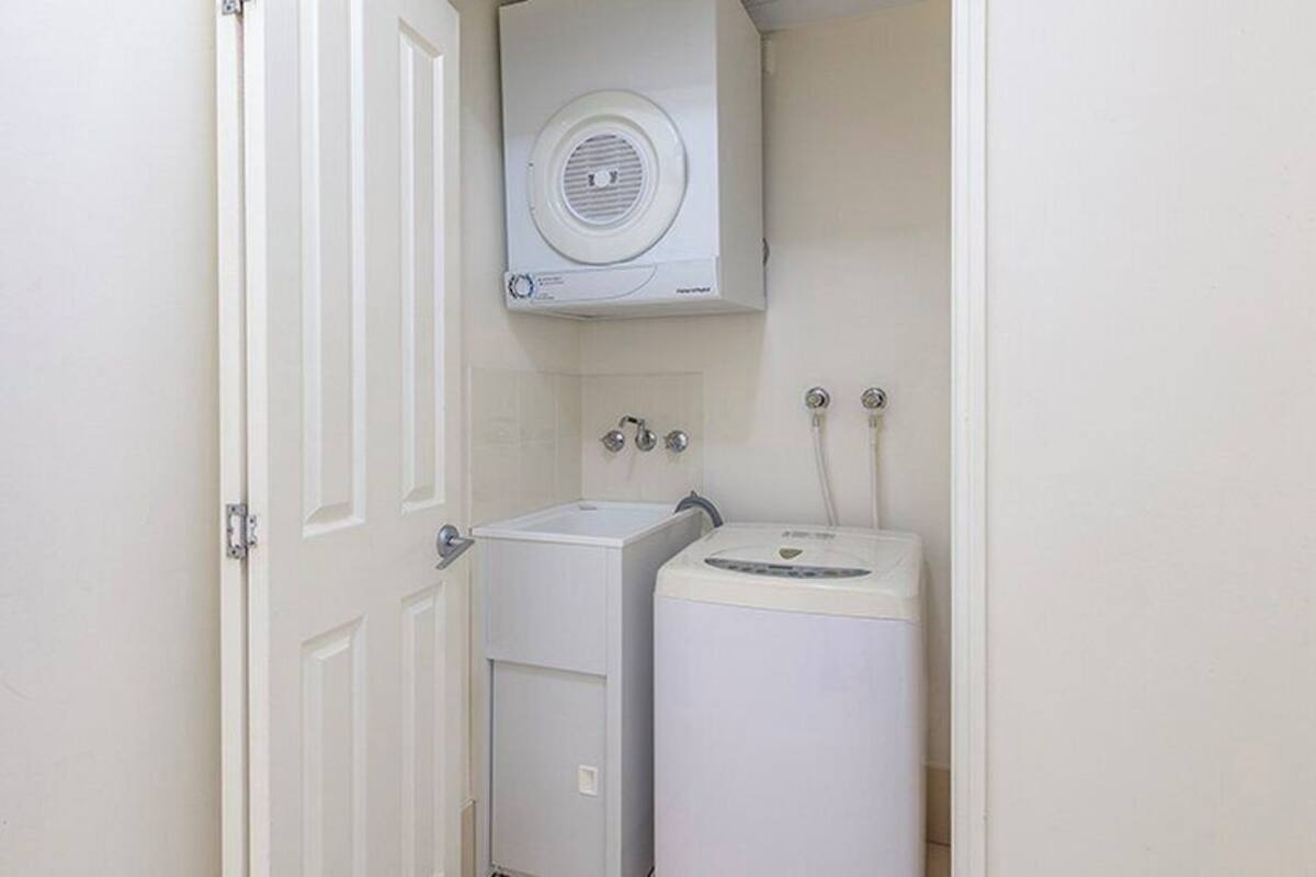 Una sala de lavandería con lavadora y secadora, una puerta blanca y un calentador fijado a la pared.
