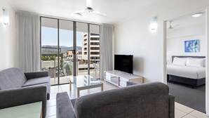 Una habitación de hotel moderna con balcón, televisión de pantalla plana, sofá y cama.