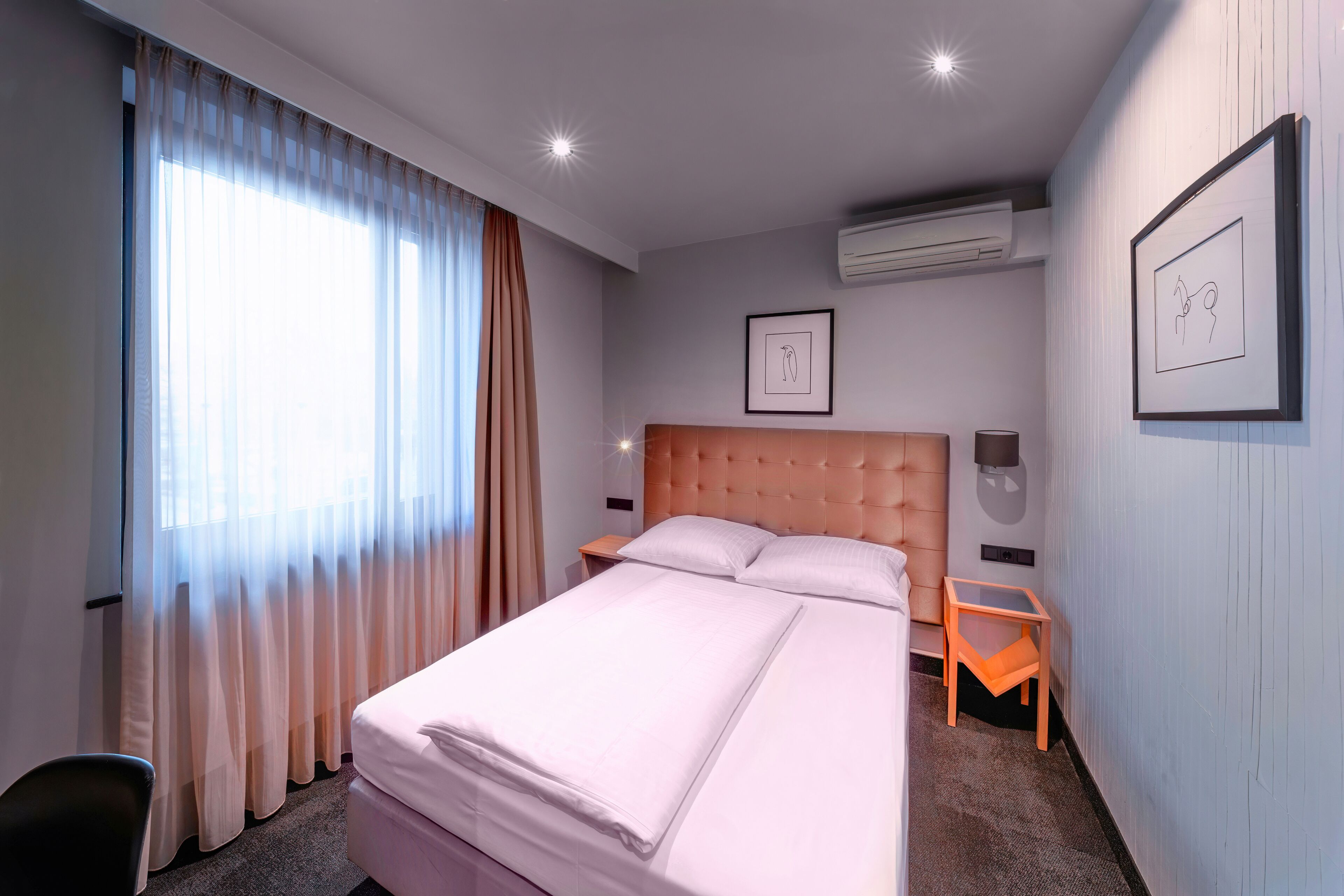 Une chambre d’hôtel avec un grand lit, une table de chevet, une chaise et un tableau encadré au mur.