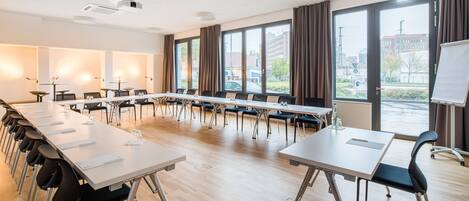 A conference room with a long table, chairs, and a projector.