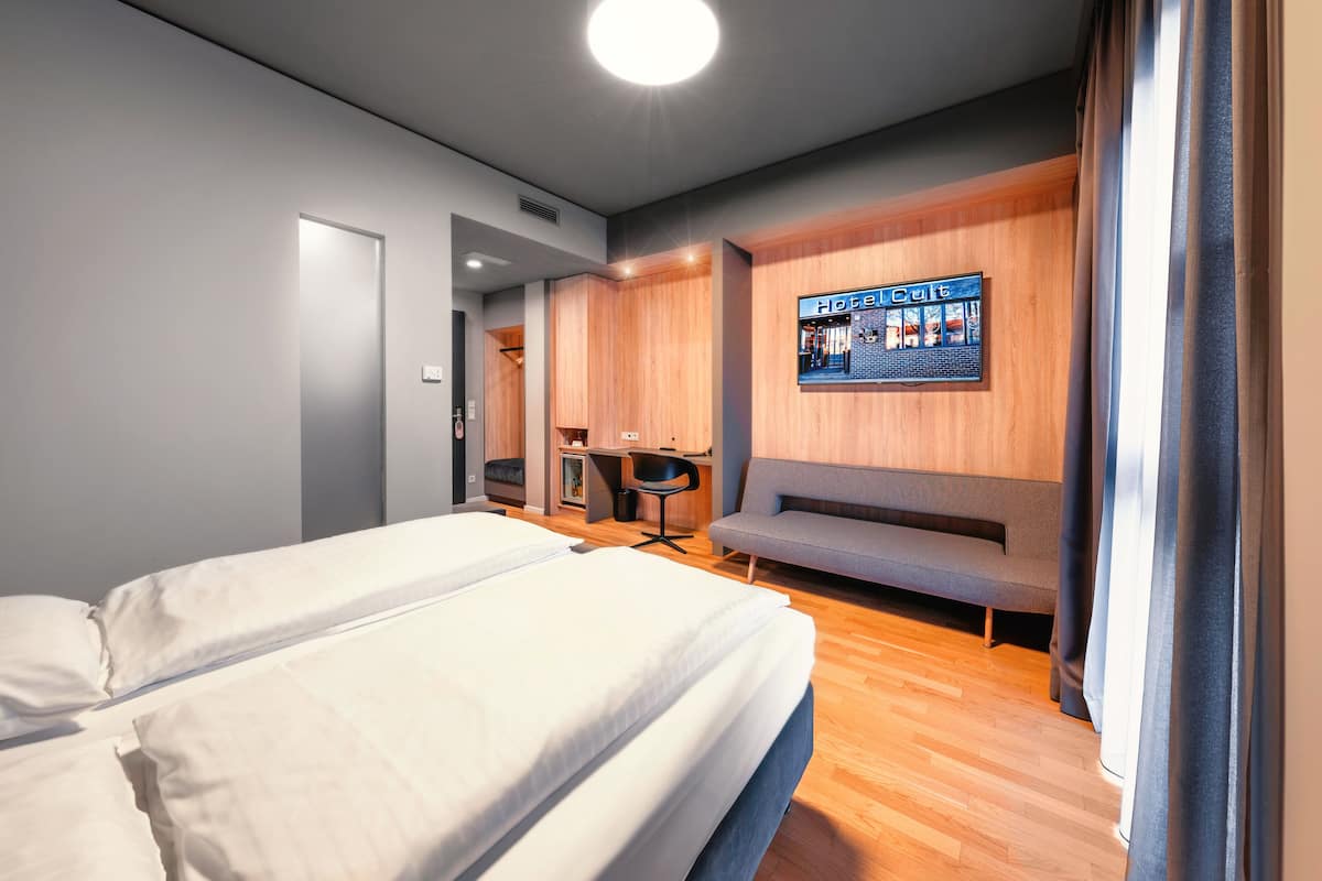 A hotel room with a bed, a desk, a chair, and a seating area.