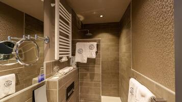A modern bathroom with a shower, a toilet, and a sink. There are towels hanging on the wall and a mirror above the sink.
