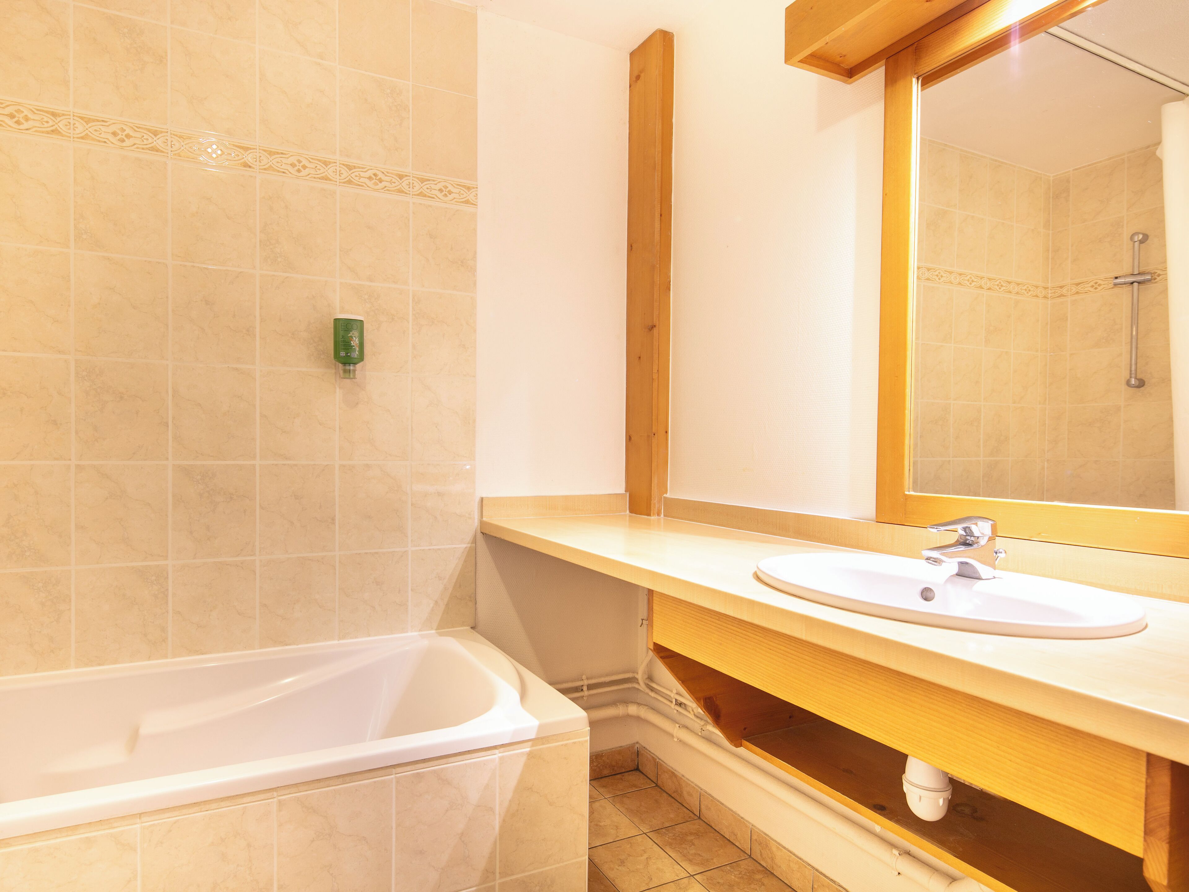A bathroom with a bathtub, a sink, and a mirror.