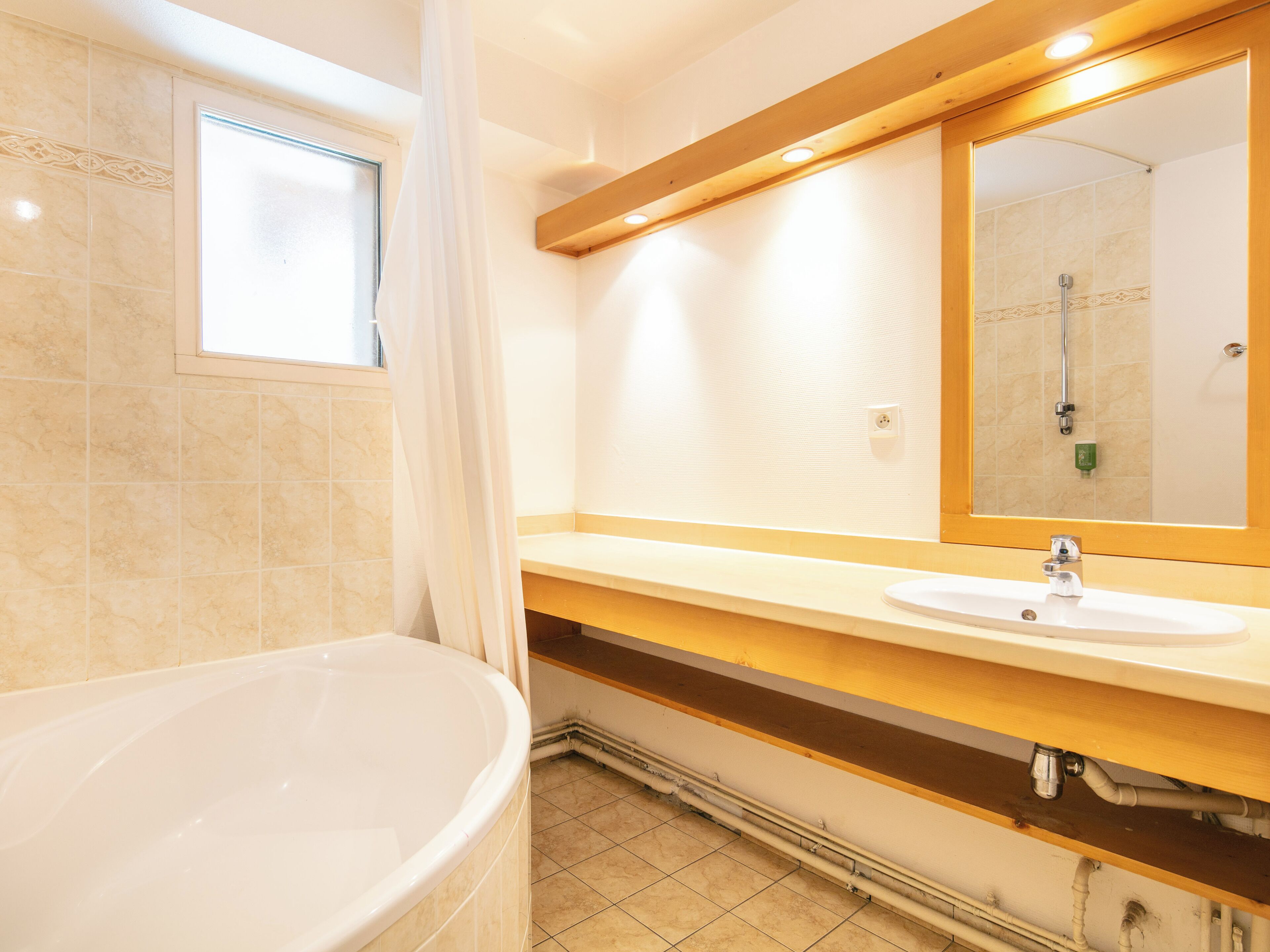 A bathroom with a bathtub, sink, and a large mirror.