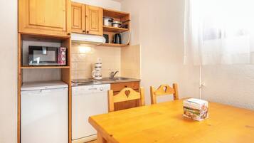 A compact kitchen with wooden cabinets, a microwave, a coffee maker, and a dishwasher.