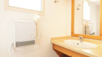 A bathroom with a white sink, wooden vanity, a mirror, and a hairdryer.