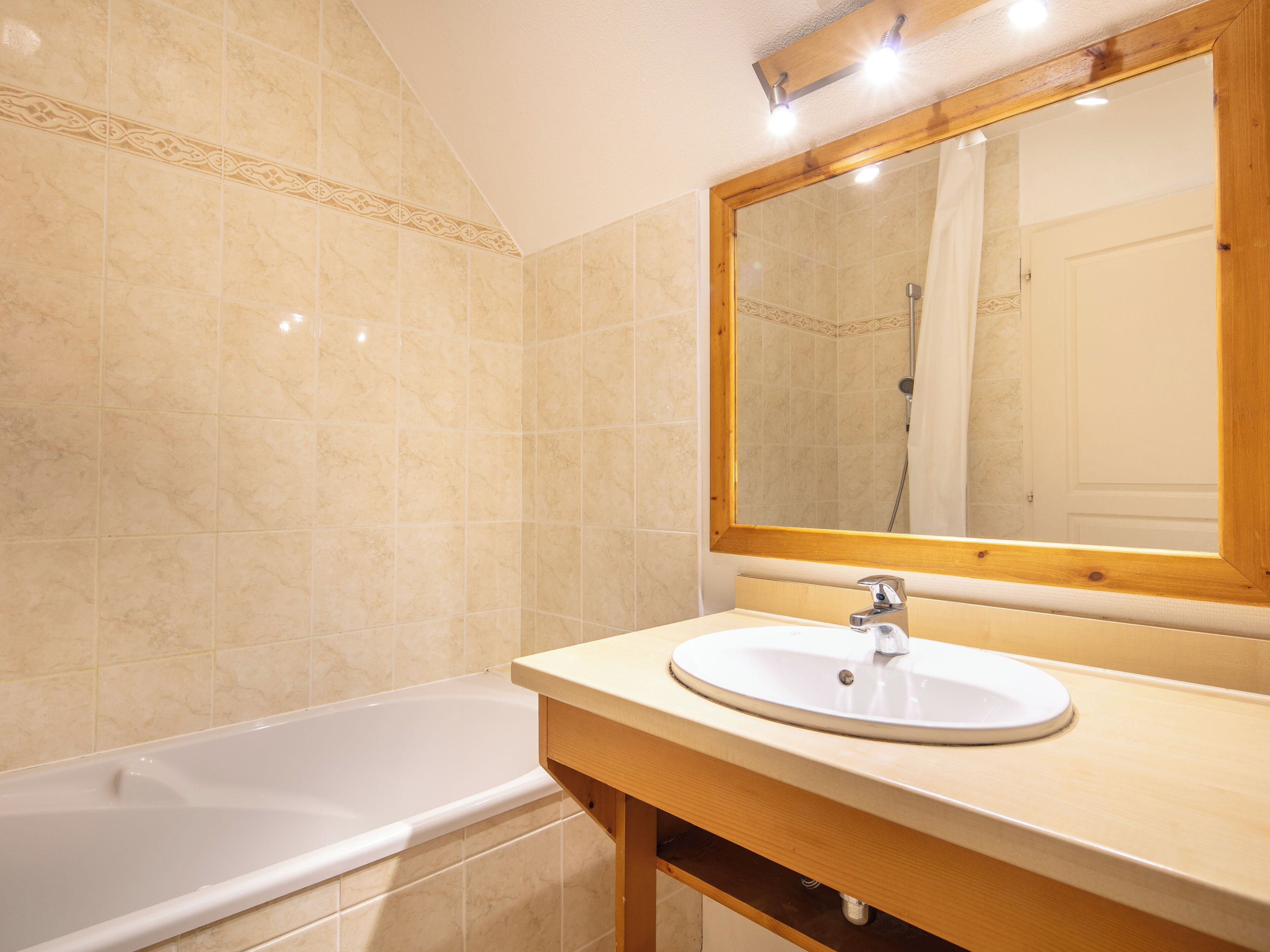 A bathroom with a bathtub, a sink, and a mirror.