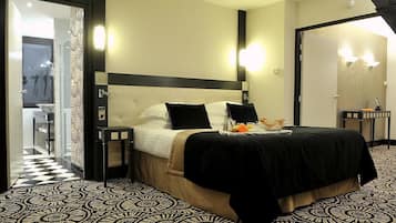 A hotel room with a bed, bedside tables, a bathroom visible through an open door, and a patterned floor.