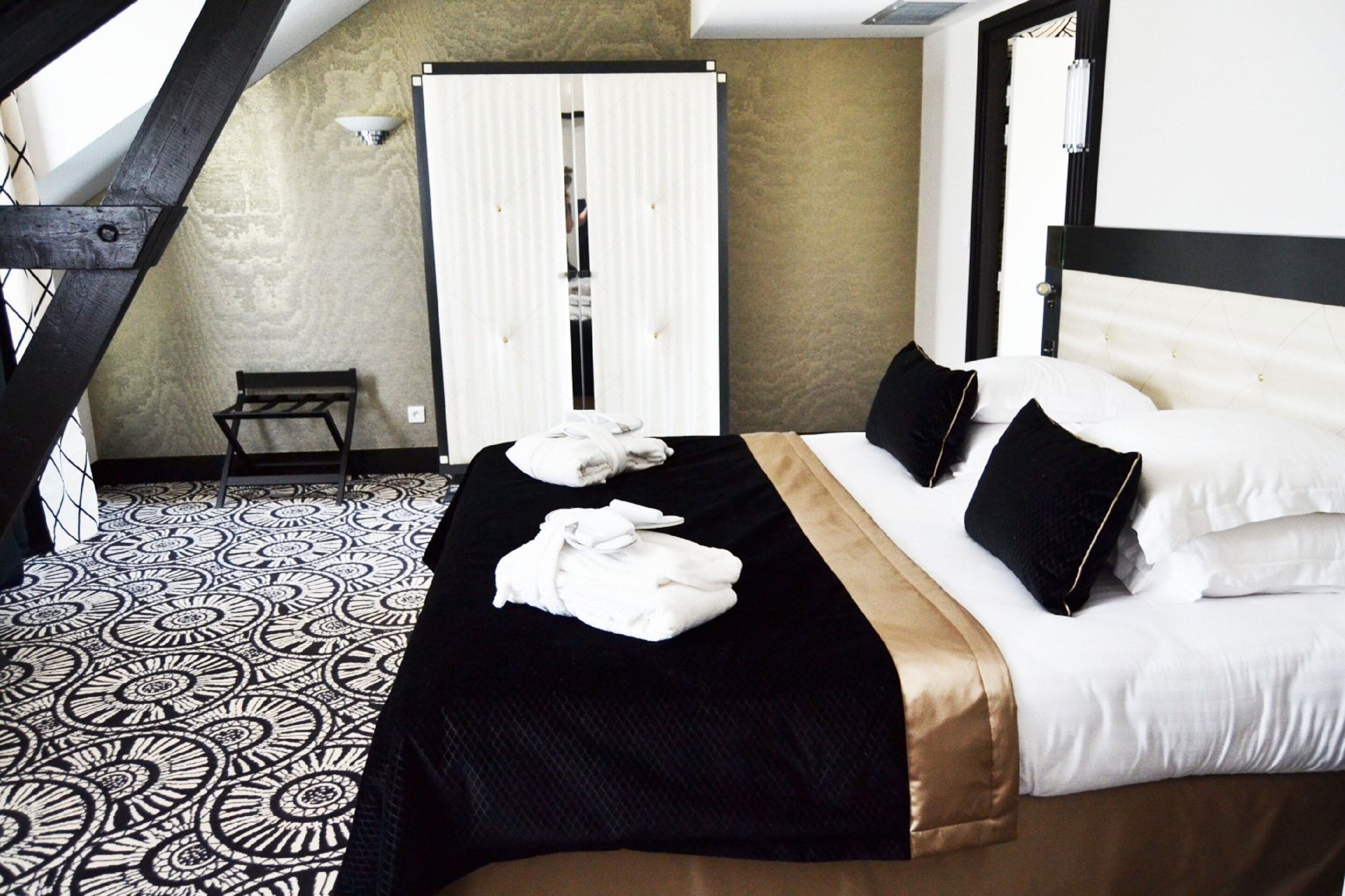 Habitación de hotel con cama, banca y piso estampado.