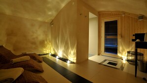 A spa room with a massage table, towels, a wooden wall, and a small window. - Hotel Jehan de Beauce (Chartres)