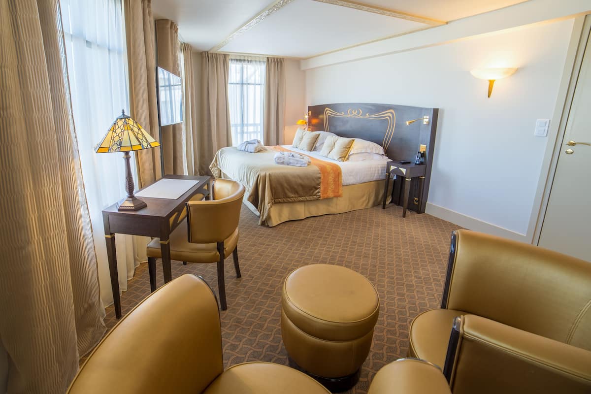 A hotel room with a bed, a desk, a chair, and an ottoman.