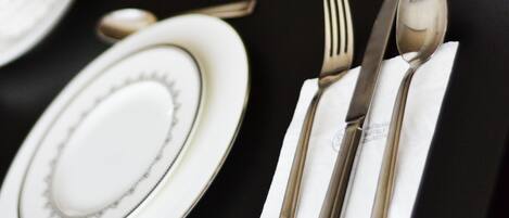 Une table mise avec soin, comprenant des assiettes, des couverts et une tasse, le tout disposé sur une nappe noire.