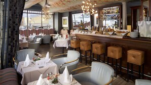 Un restaurant avec des banquettes à rayures, des tabourets de bar et un coin bar où sont exposées des bouteilles.